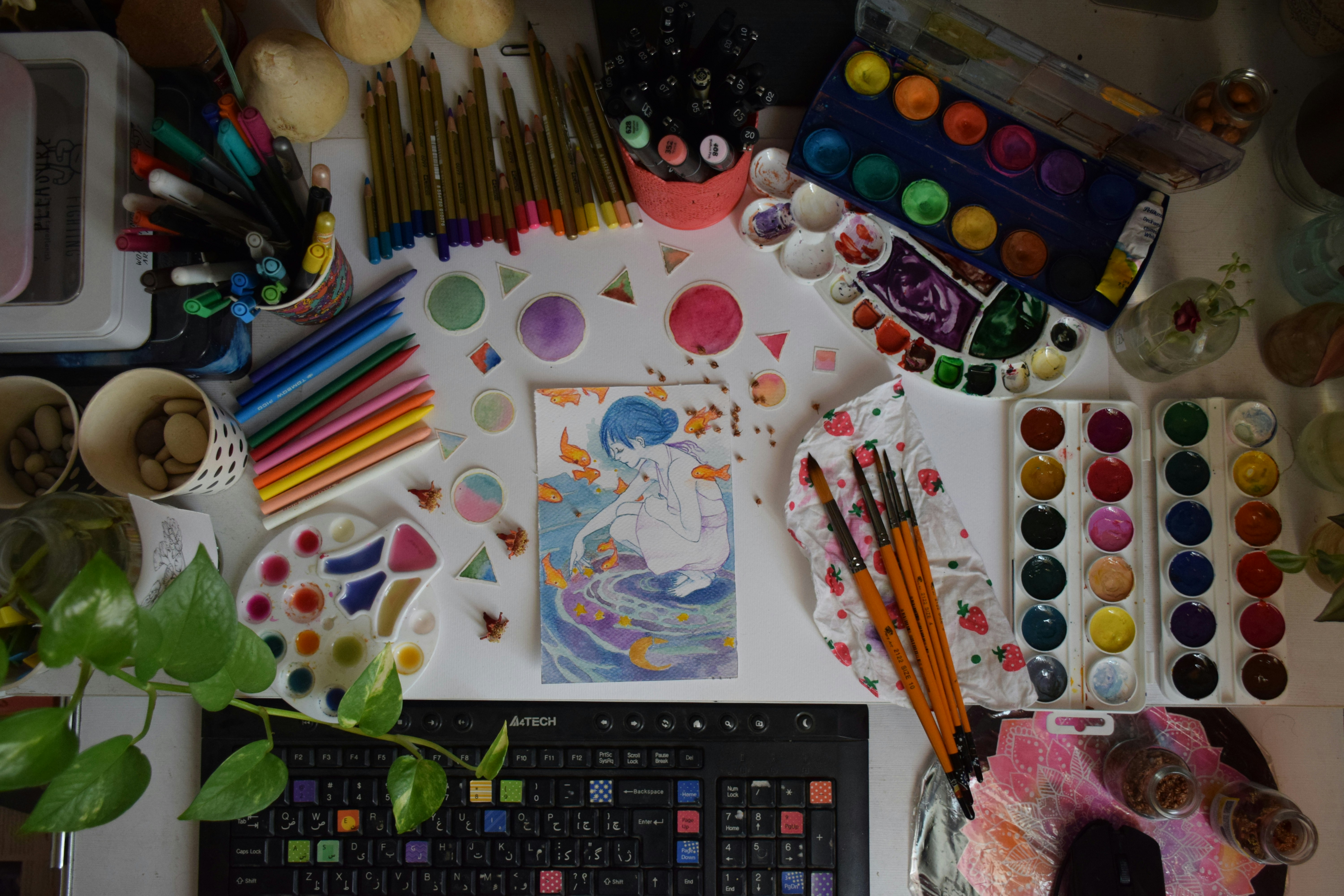 a desk covered with art supplies and a keyboard