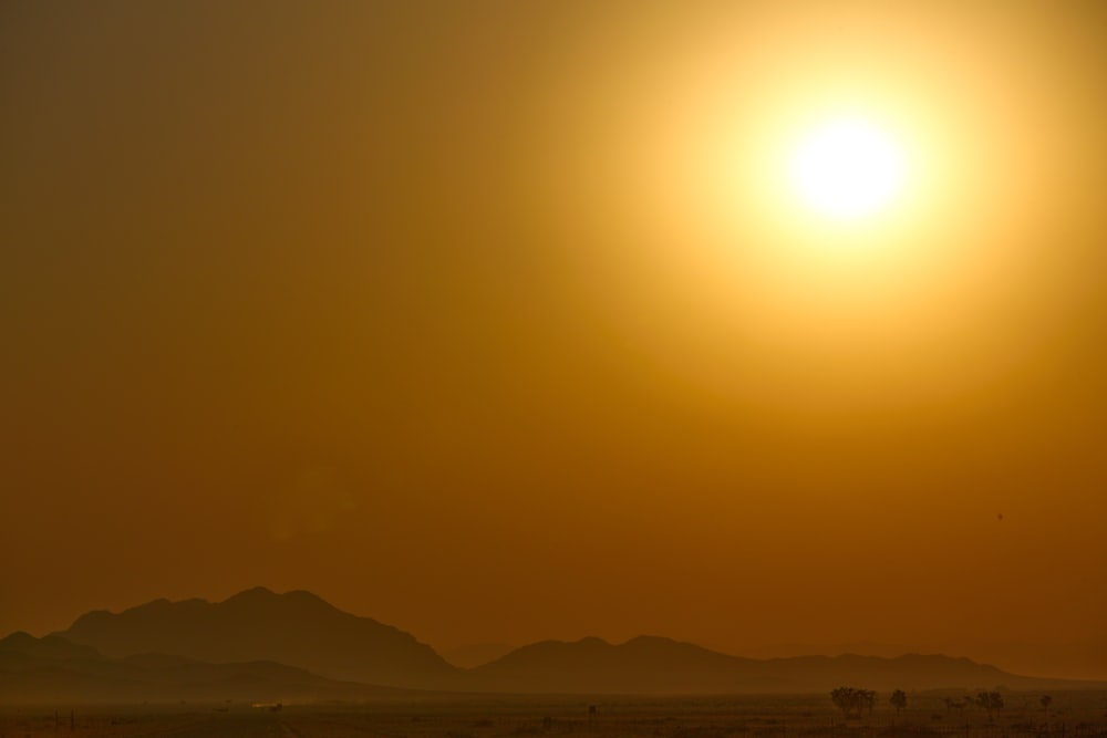 the sun is setting over the mountains in the desert