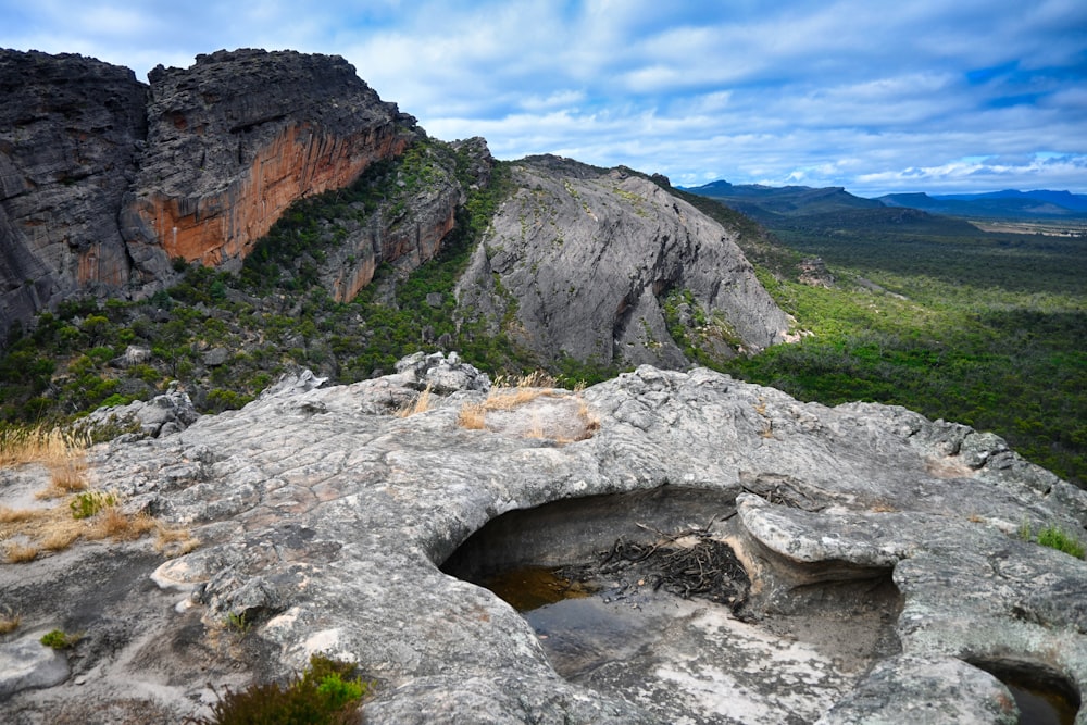 a view of a rocky outcropping with trees and mountains in the background