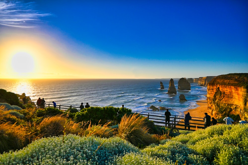 a group of people standing on top of a cliff near the ocean