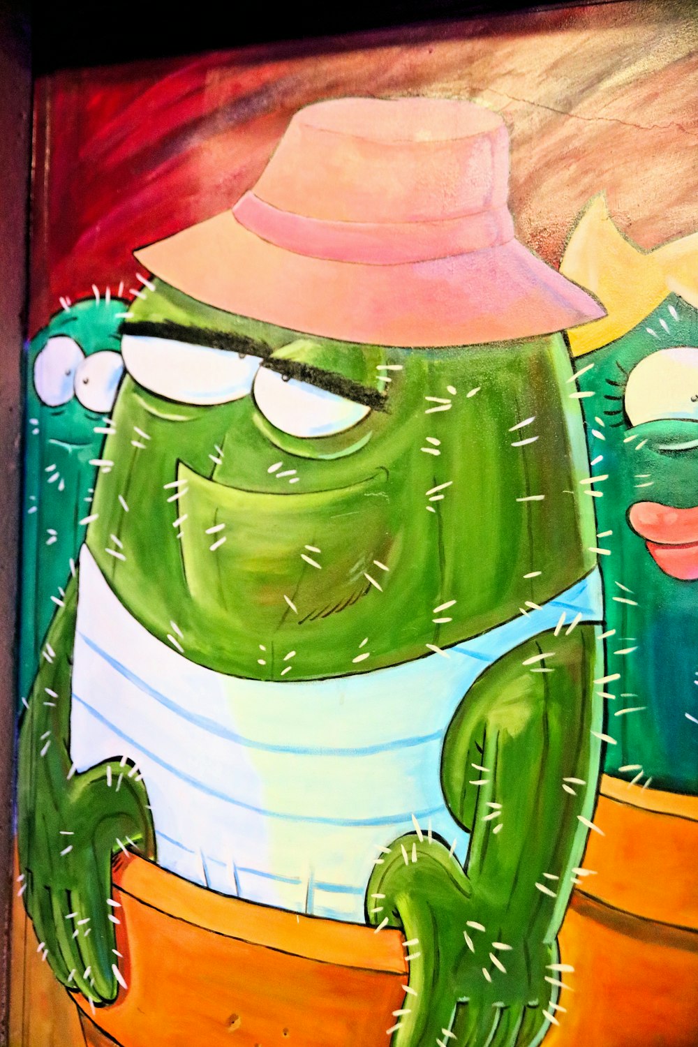 a painting of a green cactus with a pink hat