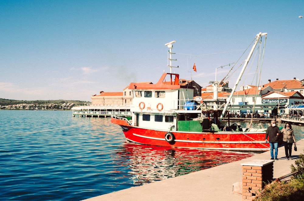 a red and white boat docked at a pier