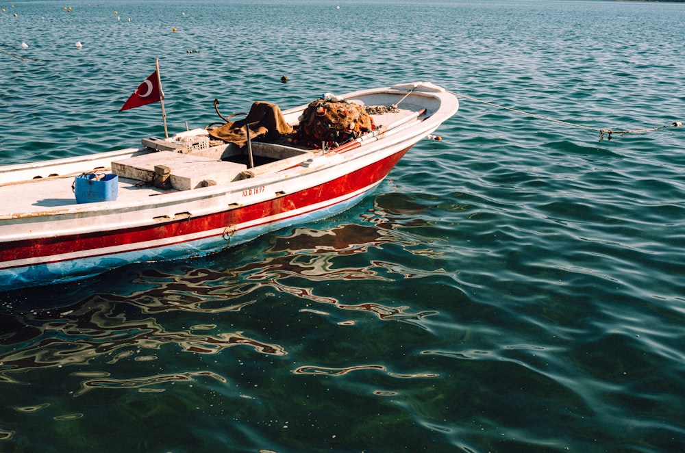 a red and white boat floating on top of a body of water