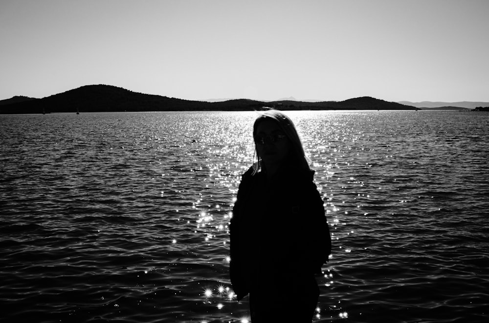 a woman standing in front of a body of water