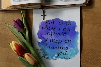 a watercolor painting of a bible and a flower