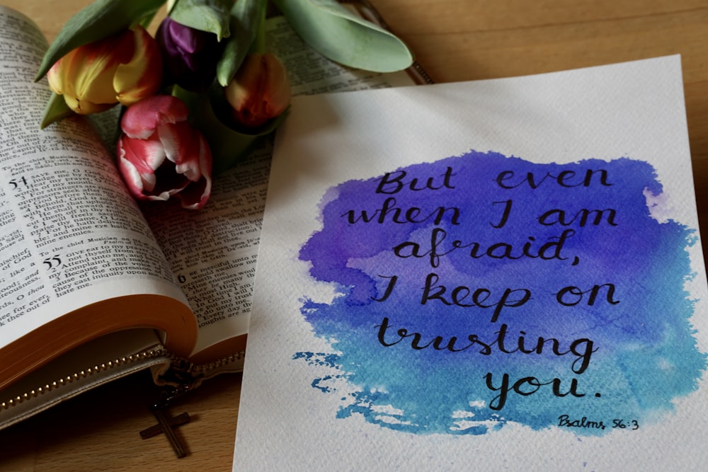 an open bible and a flower on a table