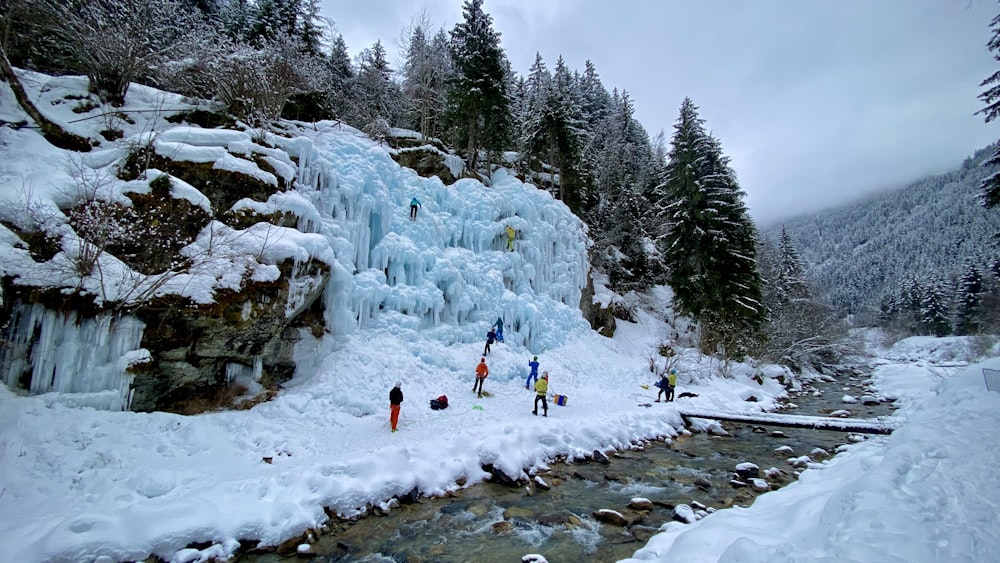 a group of people standing next to a frozen waterfall