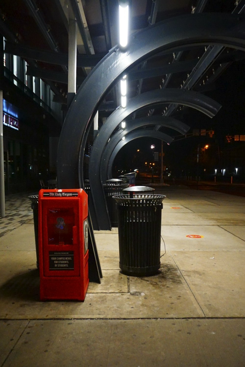 a red trash can sitting next to a black trash can