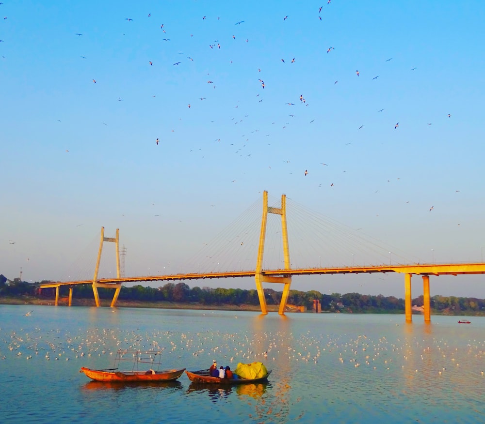 a group of boats floating on top of a lake next to a bridge