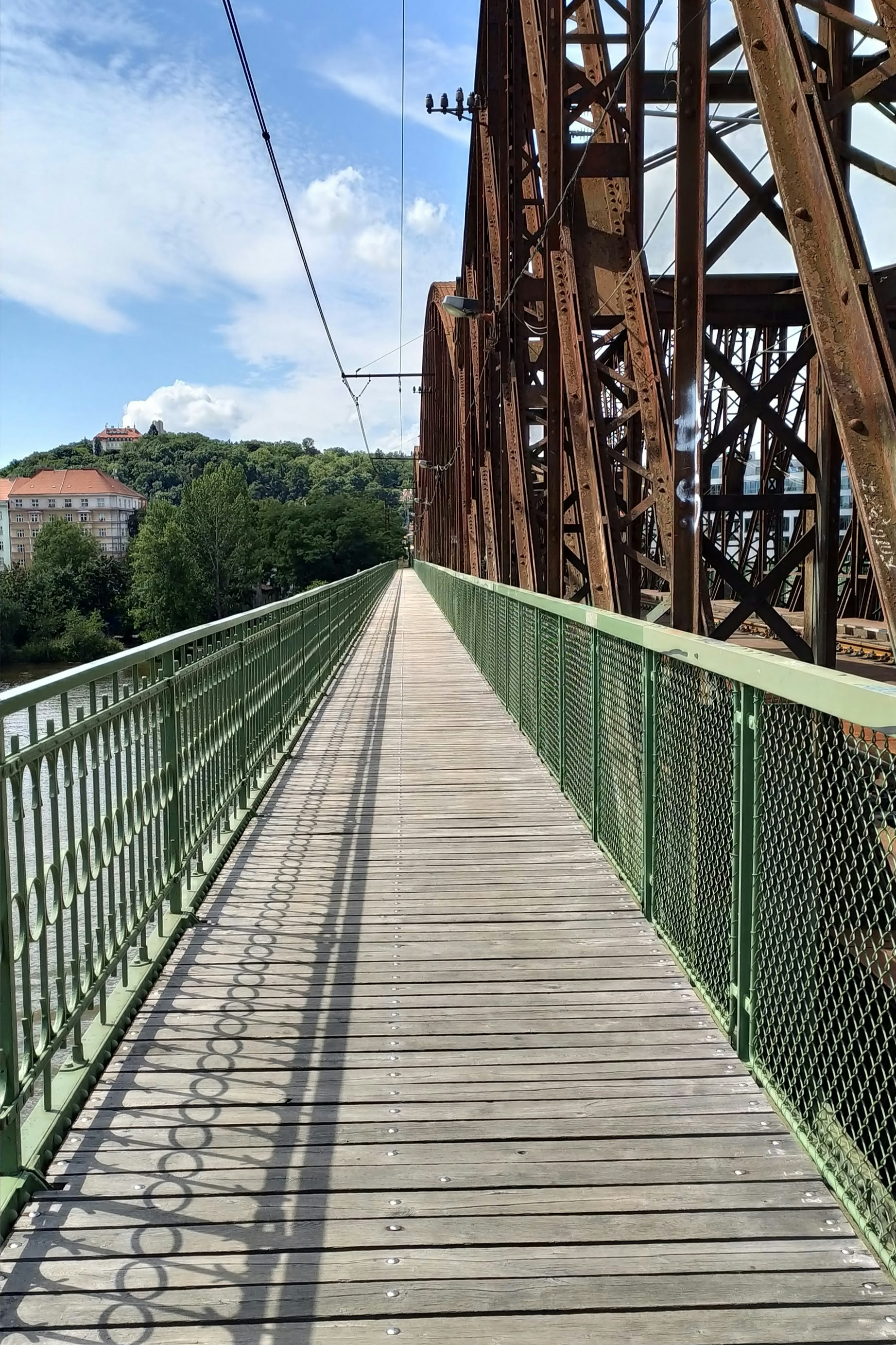 a wooden bridge with a green metal fence