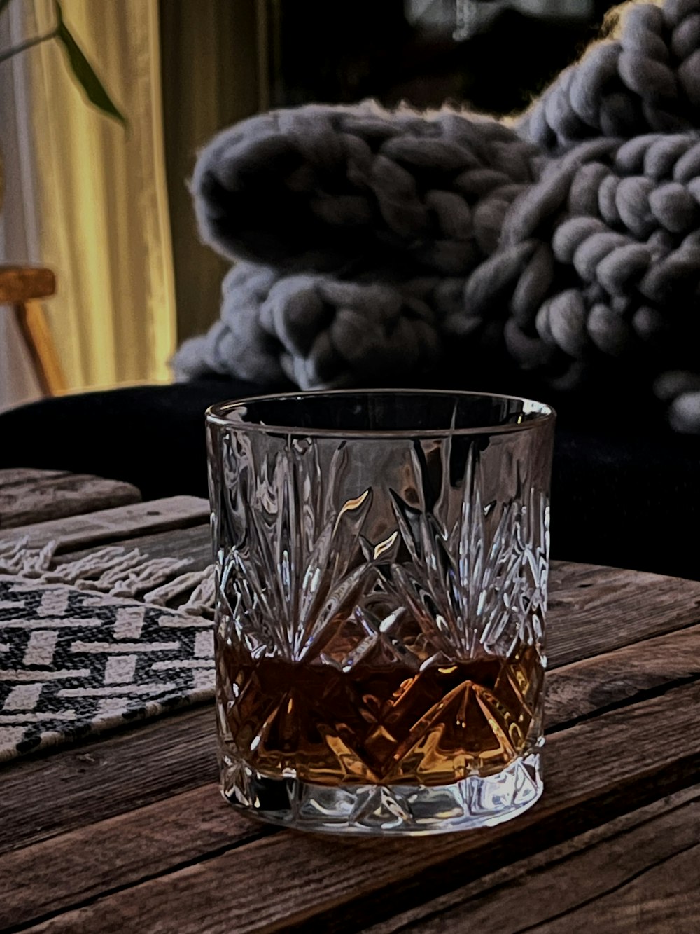 a glass of whiskey sitting on top of a wooden table