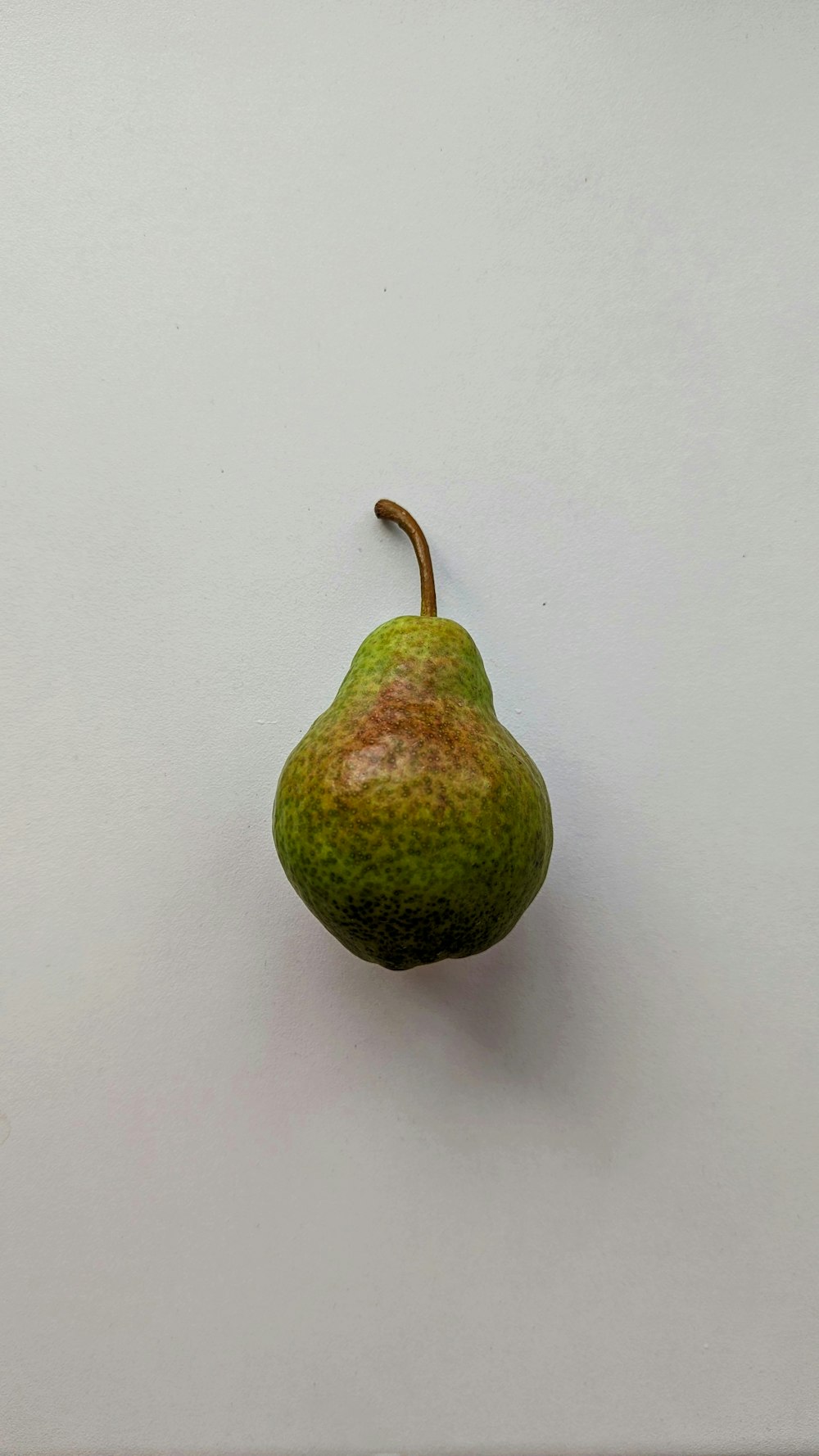 a green pear sitting on top of a white surface