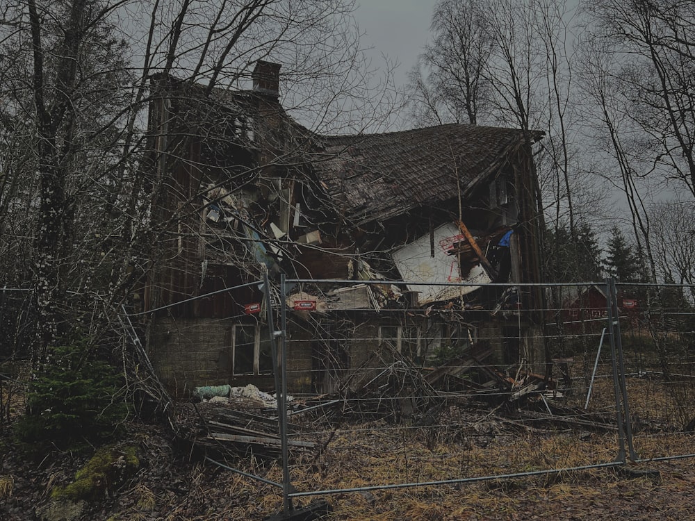 a run down house in the woods with a fence around it