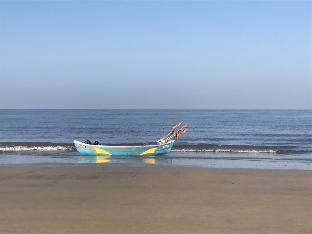 a blue and yellow boat sitting on top of a beach