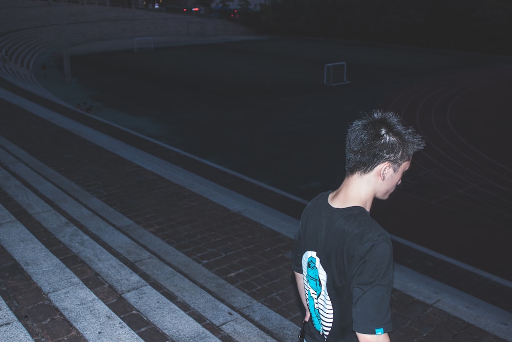 a young man walking down a brick walkway at night