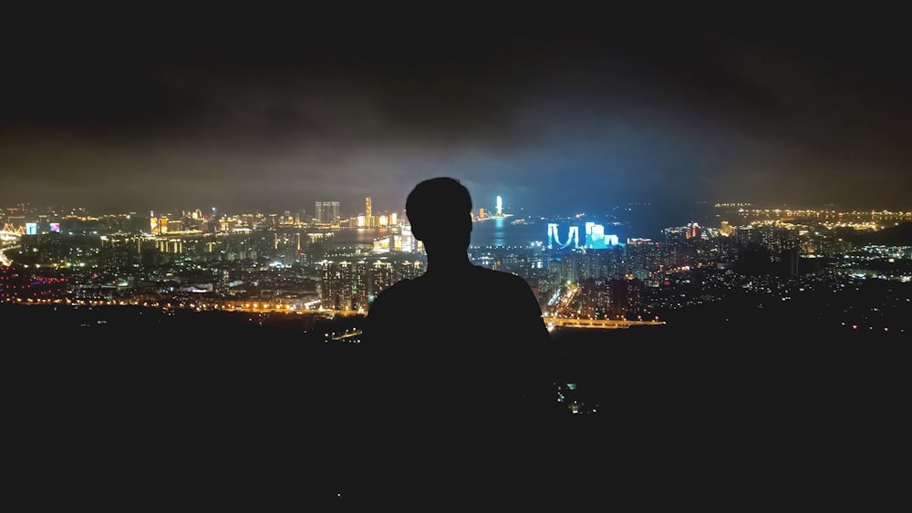 a man standing in front of a city at night