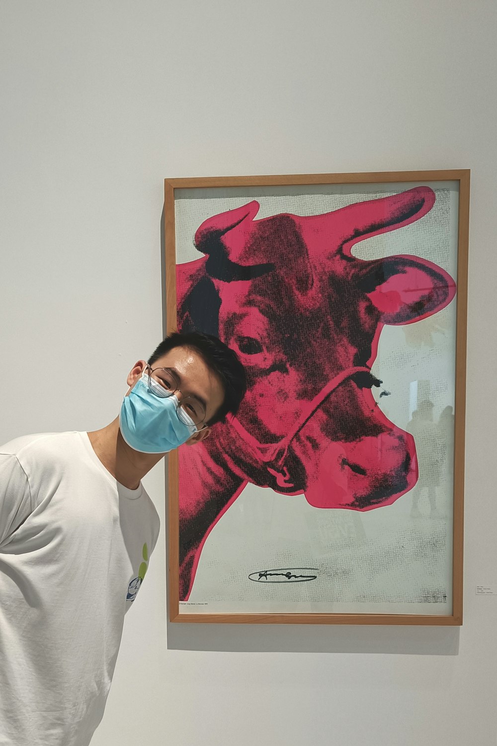 a man wearing a face mask standing in front of a painting