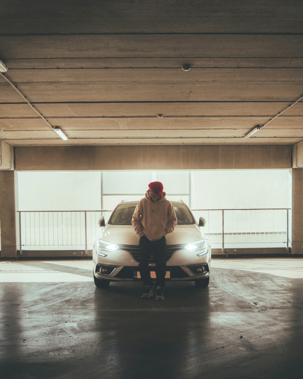 a person sitting on a car in a parking garage