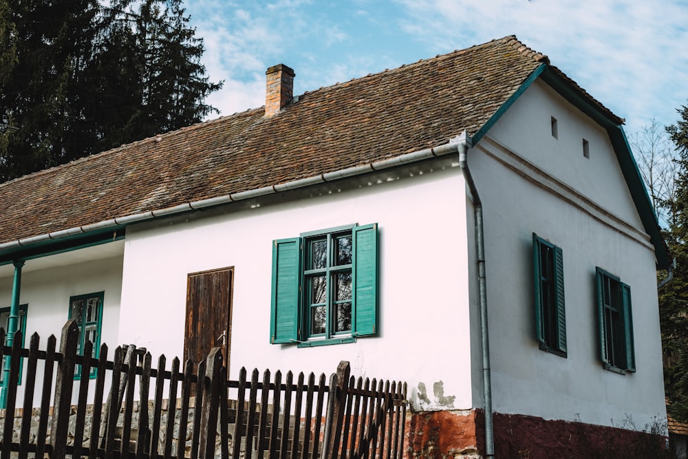 a white house with green shutters and a wooden fence