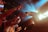 A performer on stage reaches out to a crowd of enthusiastic fans, who extend their arms towards the stage. Bright stage lights create a dynamic atmosphere with beams of blue and yellow light.