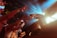 A performer on stage reaches out to a crowd of enthusiastic fans, who extend their arms towards the stage. Bright stage lights create a dynamic atmosphere with beams of blue and yellow light.