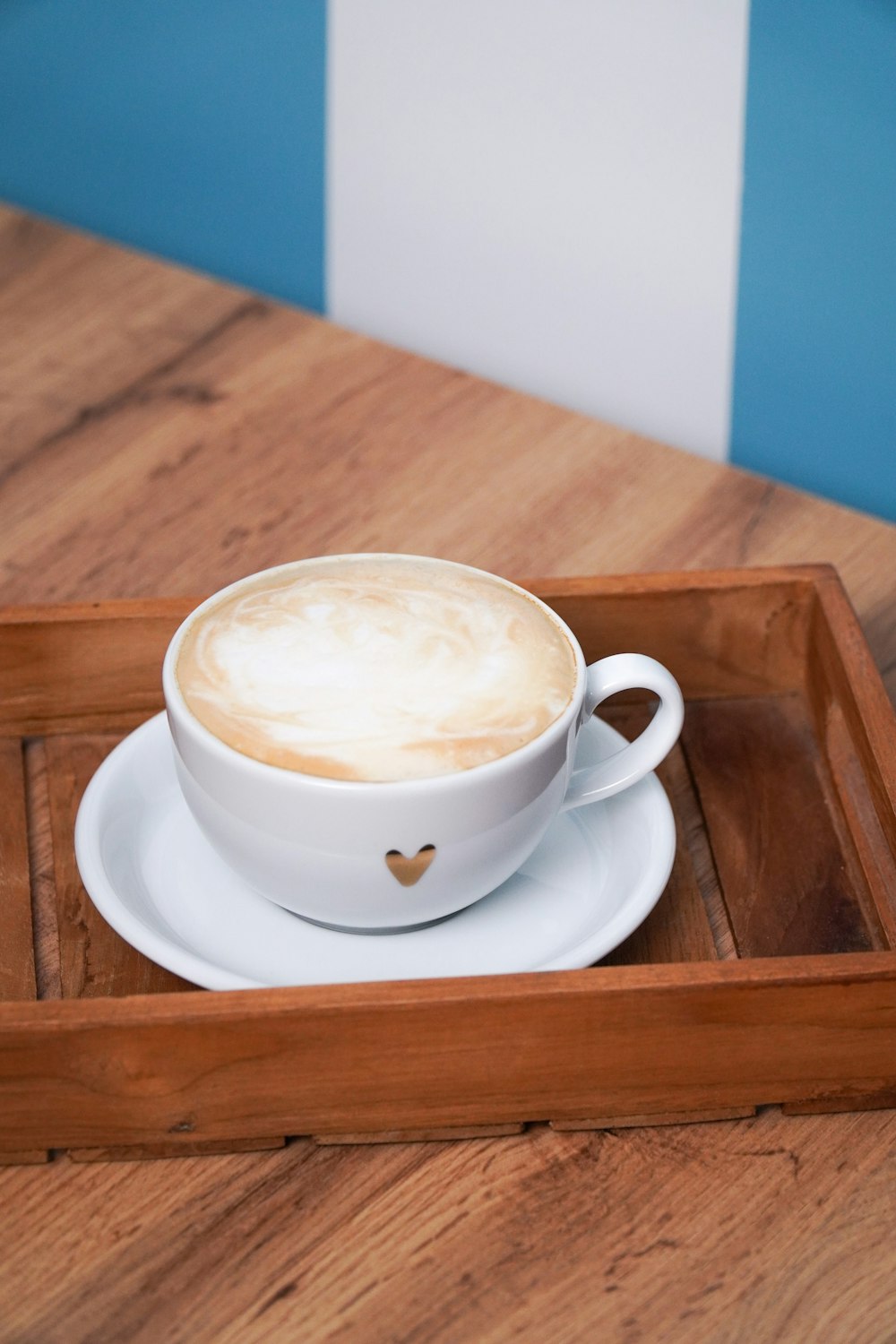a cup of cappuccino on a wooden tray