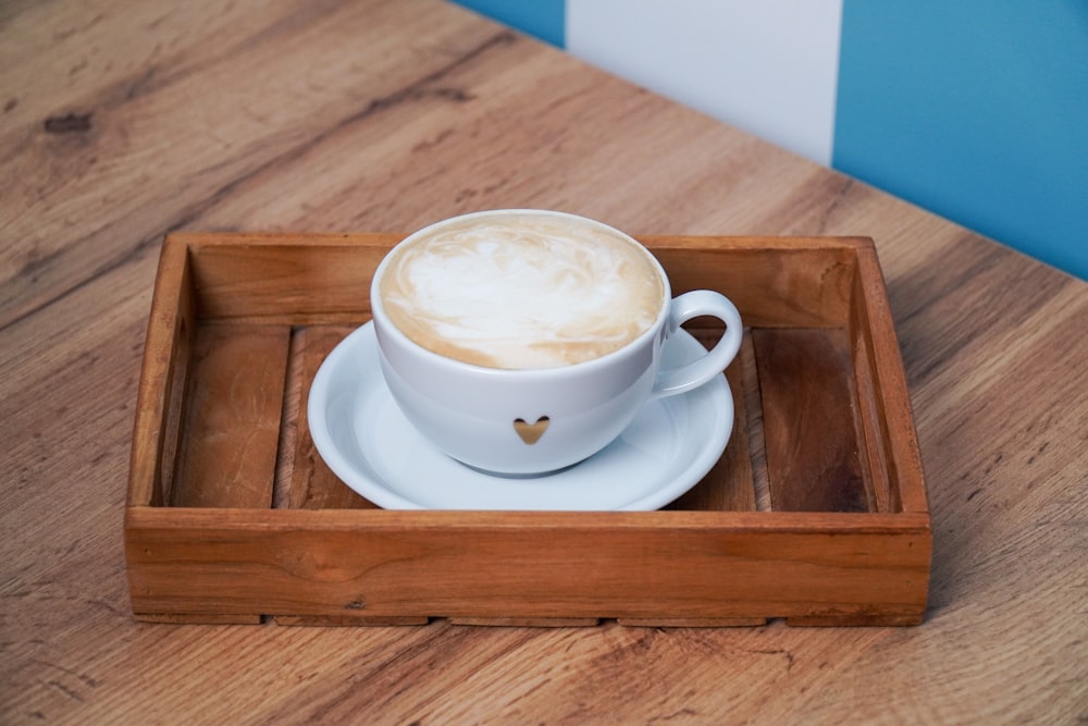 a cup of cappuccino on a wooden tray