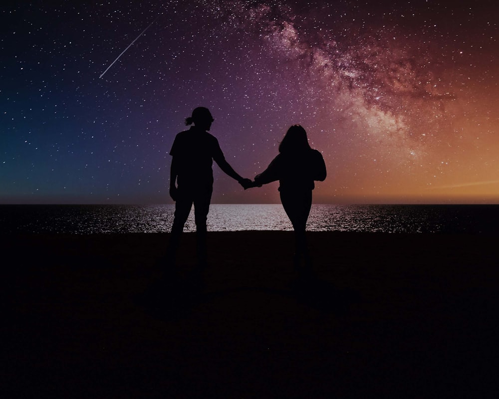 two people holding hands with the night sky in the background