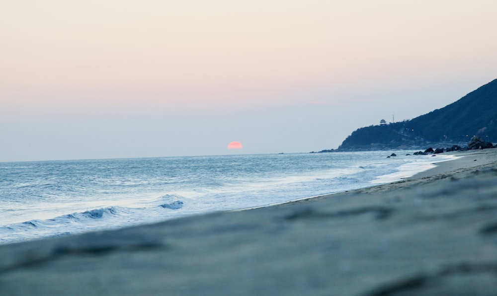 the sun is setting over the ocean at the beach