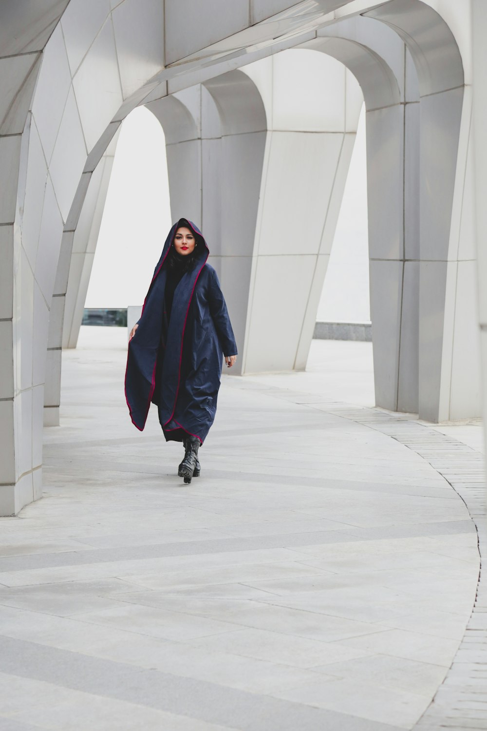 a woman in a blue coat walking down a walkway