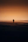 a person walking on a beach at sunset