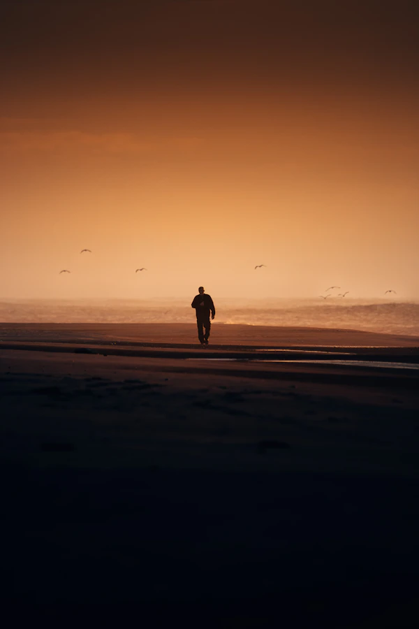 A person walking on a beach at sunset representing a fresh start and freedom from habit