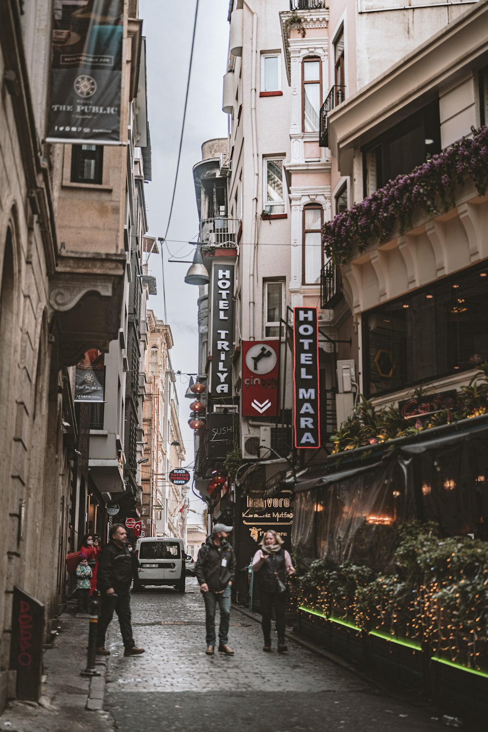 a group of people walking down a street next to tall buildings