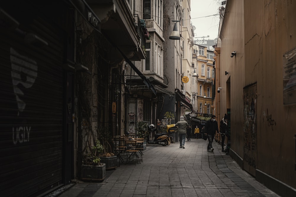 a narrow city street with people walking down it