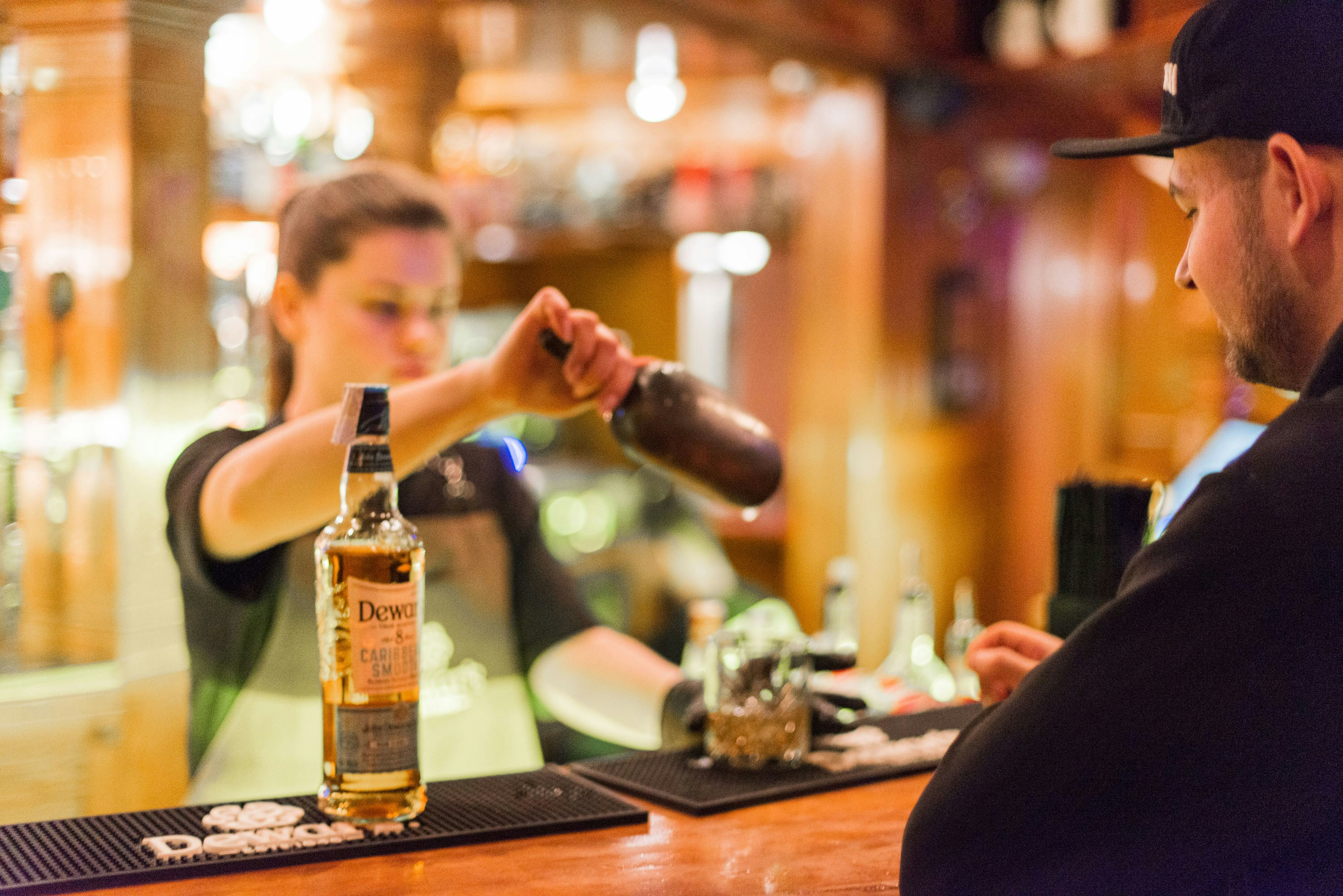 Bartender pouring a drink at a warm-lit bar