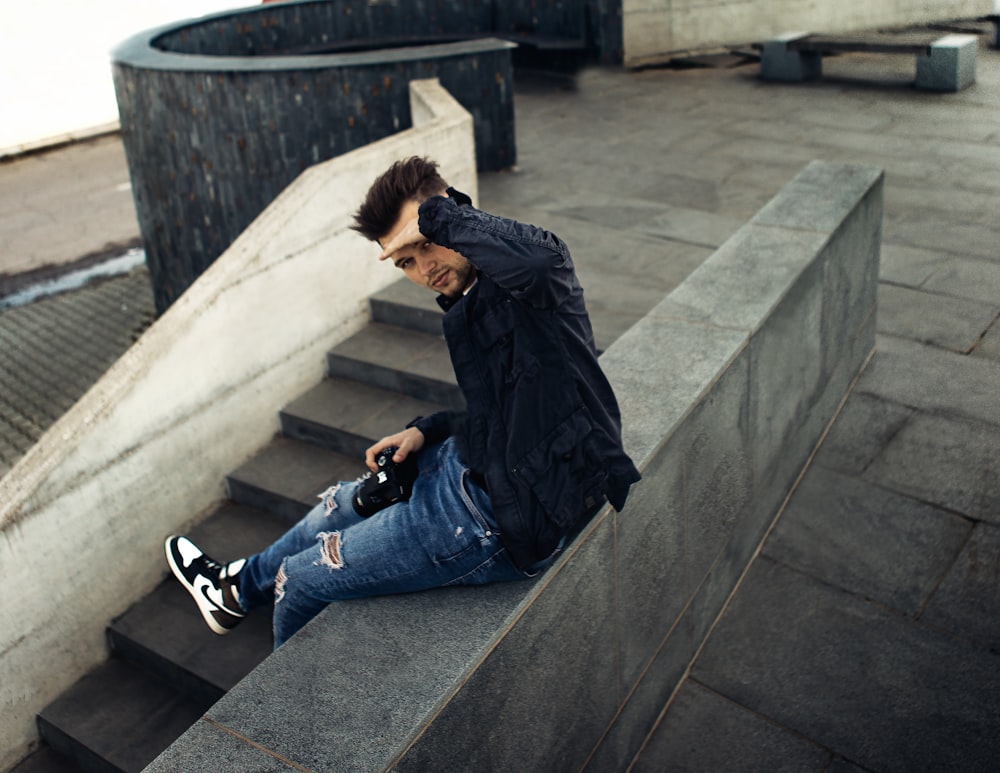 a man sitting on a ledge looking at his cell phone