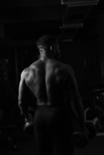 a man with no shirt is holding a dumbbell