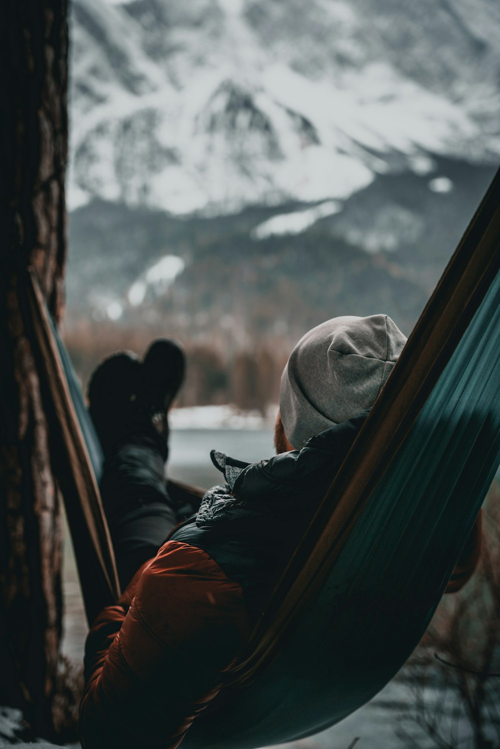 a person laying in a hammock next to a tree