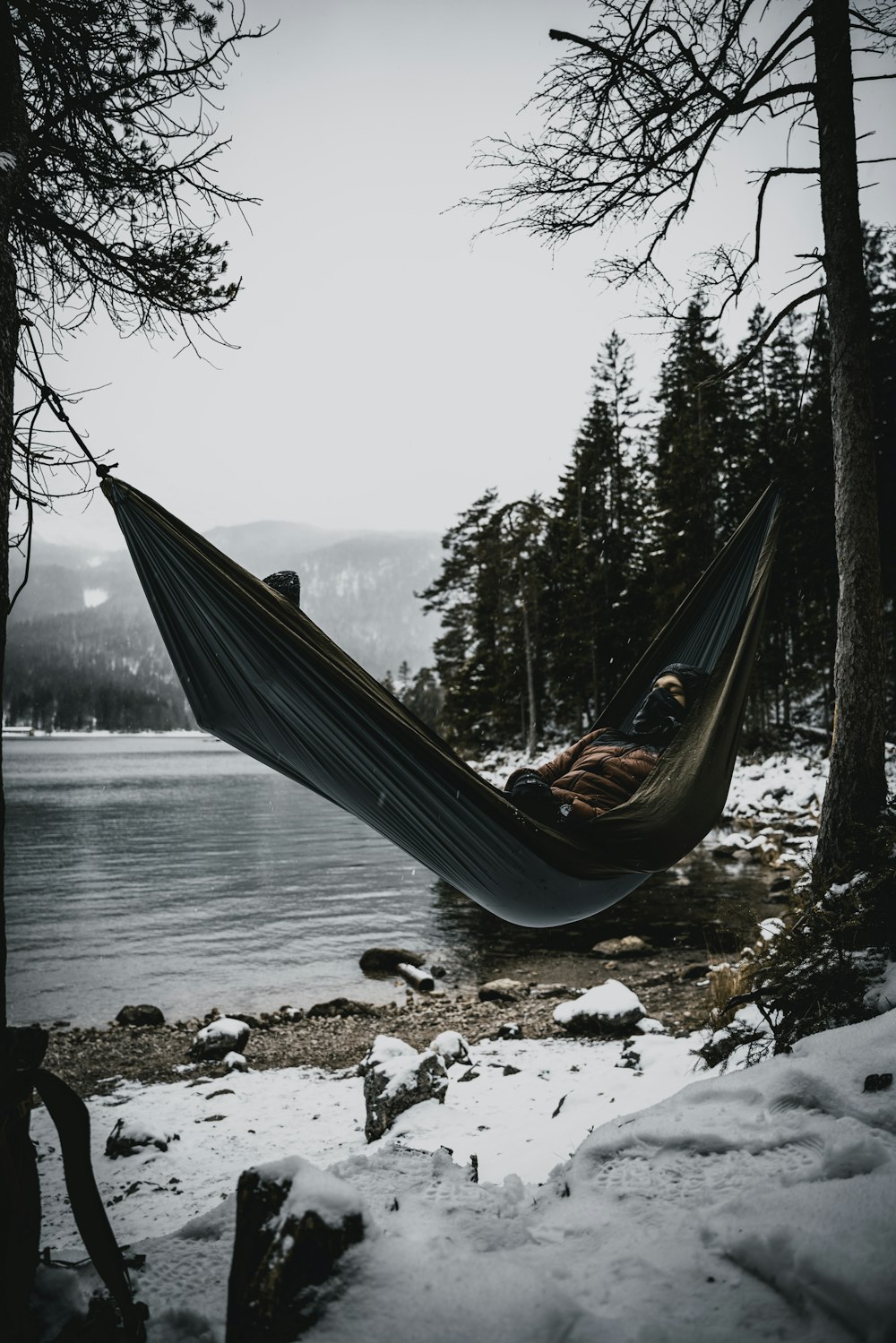 a person laying in a hammock by a lake