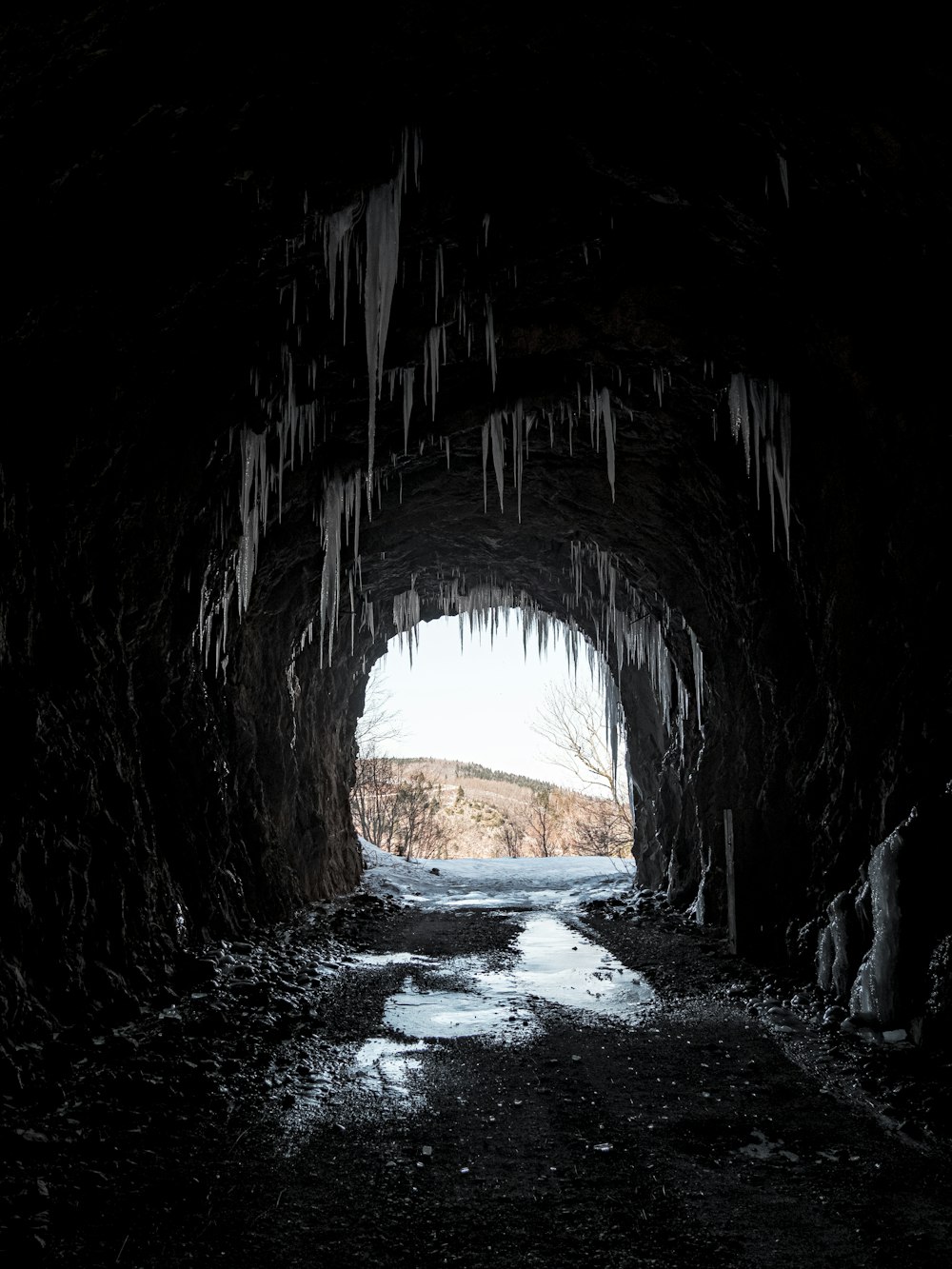 a dark tunnel with icicles hanging from the ceiling