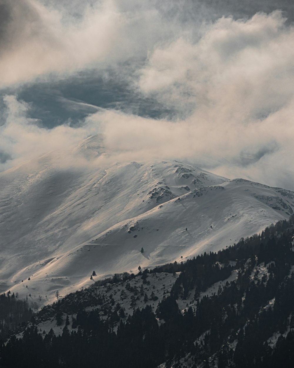 a mountain covered in snow under a cloudy sky