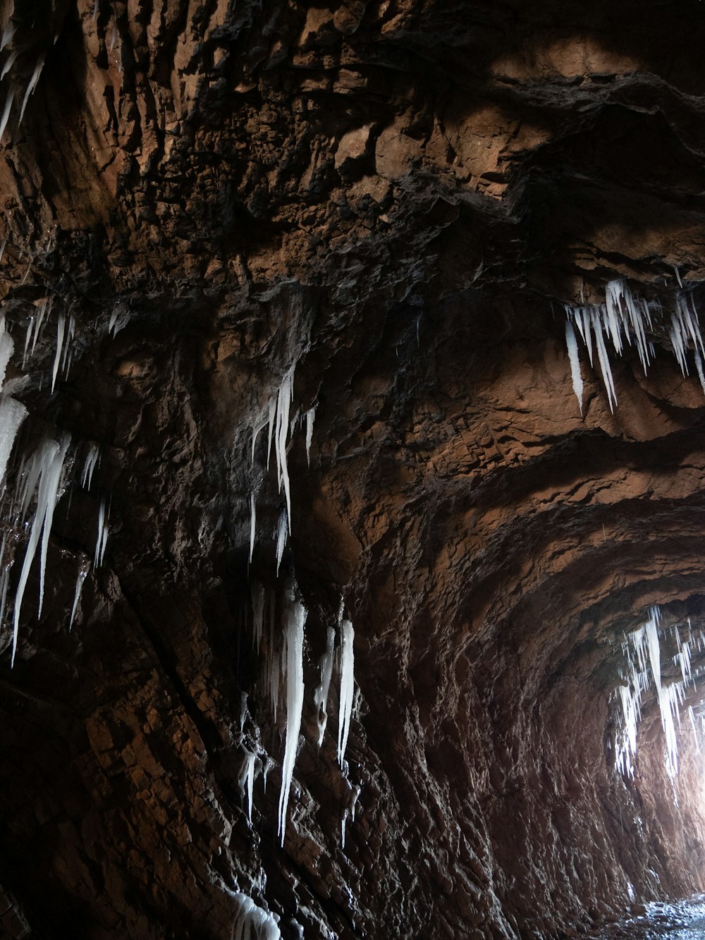 a cave filled with lots of ice hanging from the ceiling