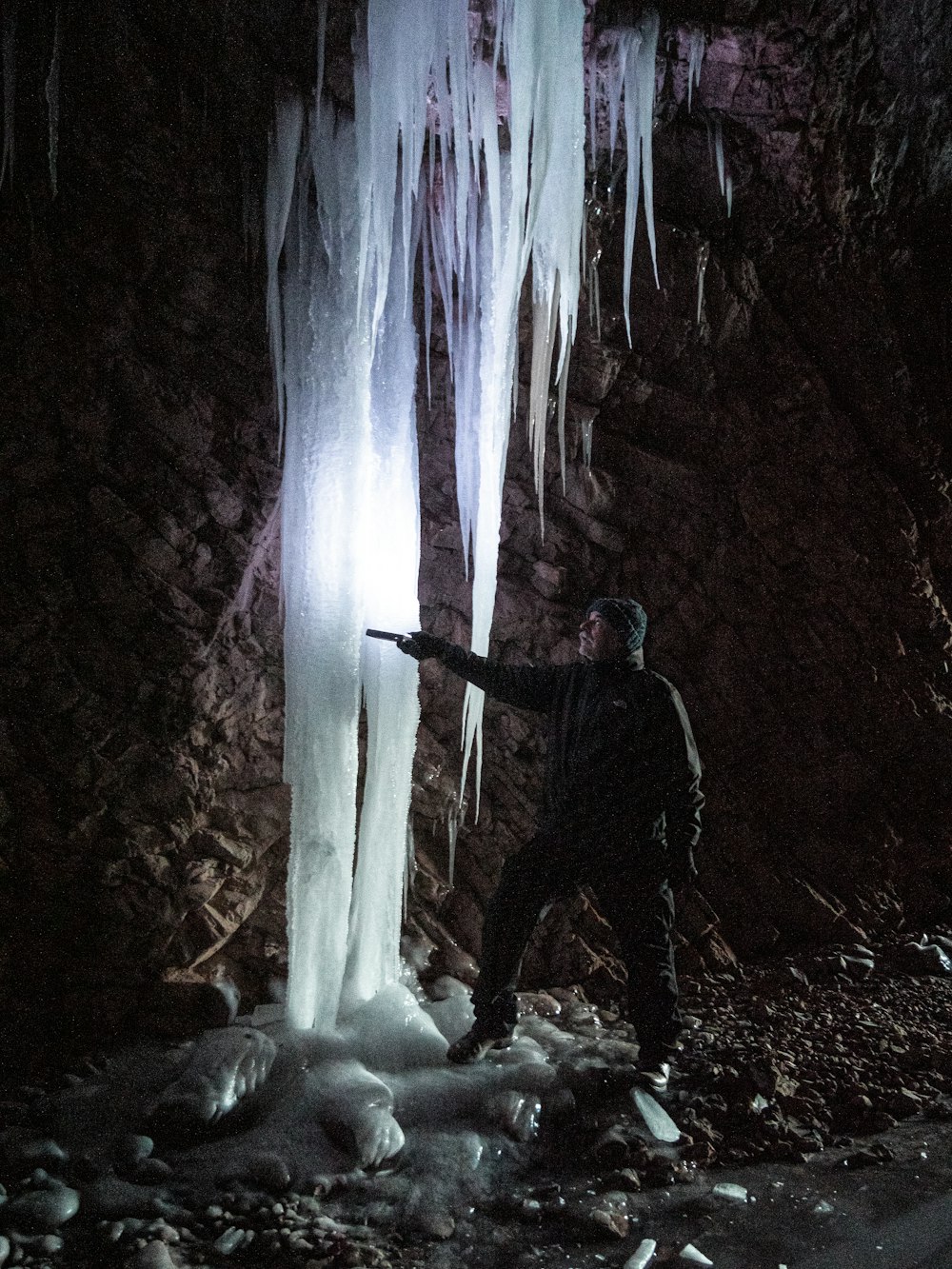 a man standing in front of a frozen waterfall