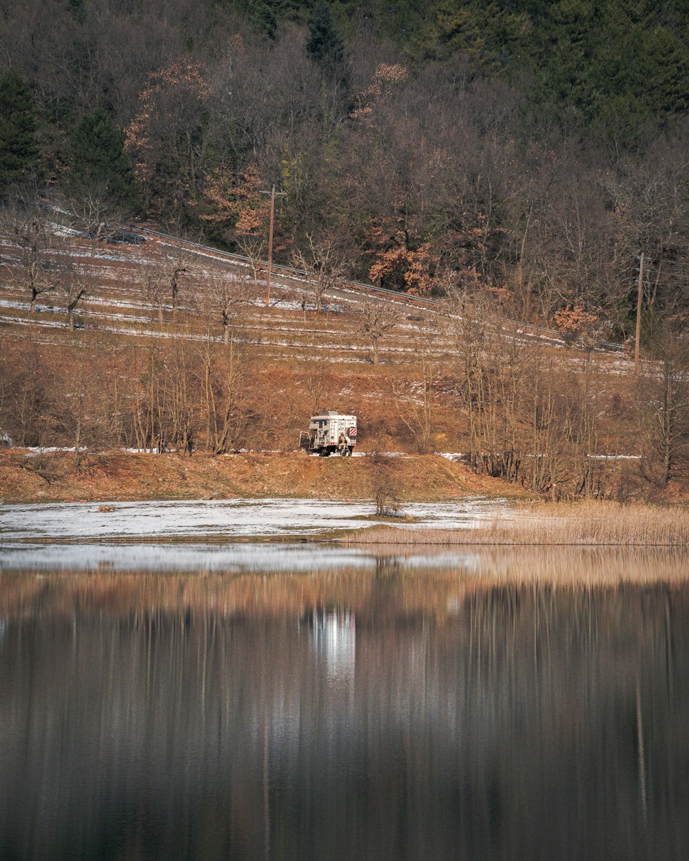a truck is parked on the shore of a lake