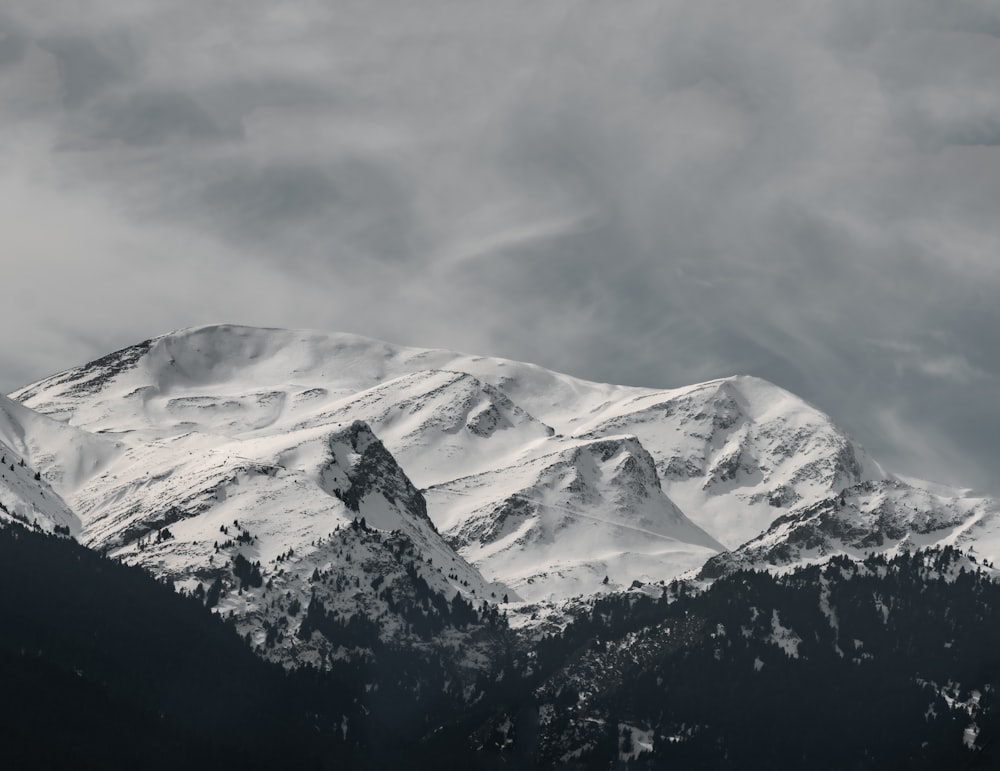 a mountain covered in snow under a cloudy sky