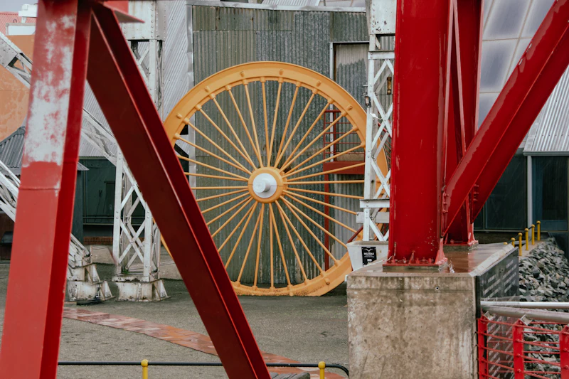 Large yellow and red wheel on display in front of a building