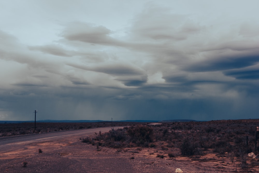 a road in the middle of a desert under a cloudy sky