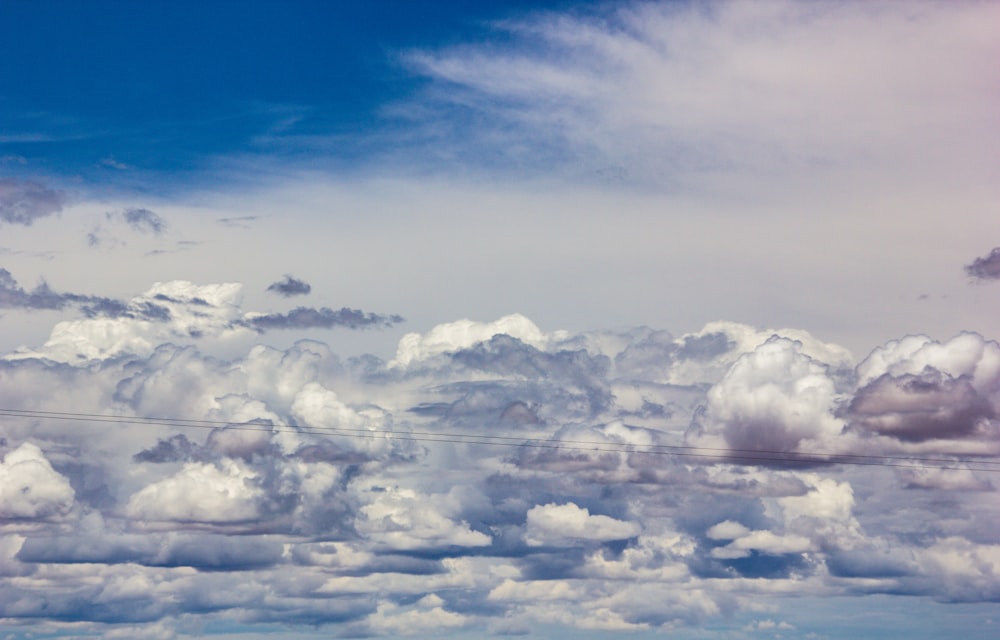 a plane flying through a cloudy blue sky