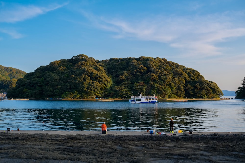 a group of people standing on a beach next to a body of water