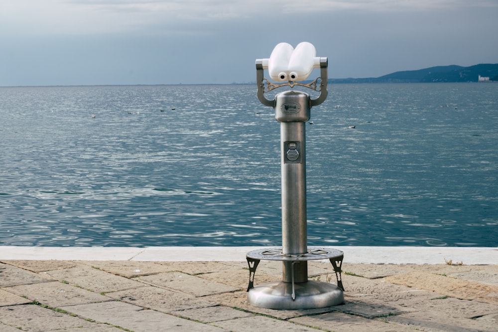 a parking meter sitting on the side of a road next to a body of water